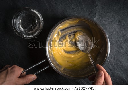 Adding flour to the melted butter on a gray table
