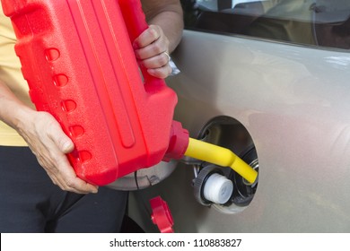 Adding fuel in car with Red Plastic Gas can (fuel container)-closeup