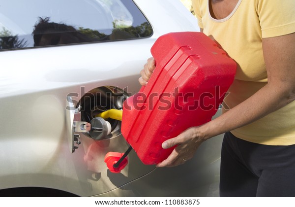 Adding fuel in car with Red Plastic\
Gas can (fuel\
container)-closeup