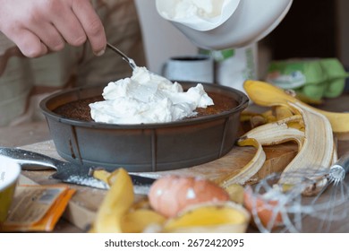 Adding generous portion of whipped cream to chocolate dessert during preparation process