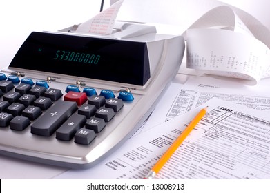 An Adding Machine Or Calculator With Adding Machine Tape Or Paper And Tax Forms