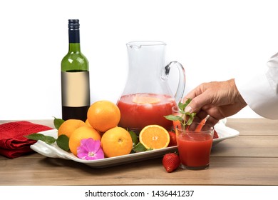 Adding  Mint Garnish To A  Glass Of Sangria Cocktail Drink With A Dark Red Wine Bottle With Generic Label Oranges And Strawberries On The Table
