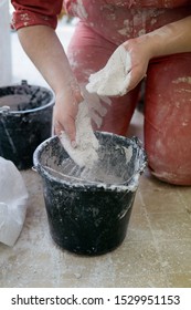 Adding The Plaster Powder To The Water In A Mixing Container By Sprinkling Or Sifting The Powder Over The Water. Preparing Plaster Mix With Sculptor Bare Hands. Basic, Essential Sculpting Supplies.