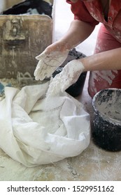 Adding The Plaster Powder To The Water In A Mixing Container By Sprinkling Or Sifting The Powder Over The Water. Preparing Plaster Mix With Sculptor Bare Hands. Basic, Essential Sculpting Supplies.