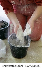 Adding The Plaster Powder To The Water In A Mixing Container By Sprinkling Or Sifting The Powder Over The Water. Preparing Plaster Mix With Sculptor Bare Hands. Basic, Essential Sculpting Supplies.