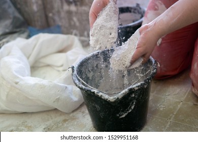 Adding The Plaster Powder To The Water In A Mixing Container By Sprinkling Or Sifting The Powder Over The Water. Preparing Plaster Mix With Sculptor Bare Hands. Basic, Essential Sculpting Supplies.