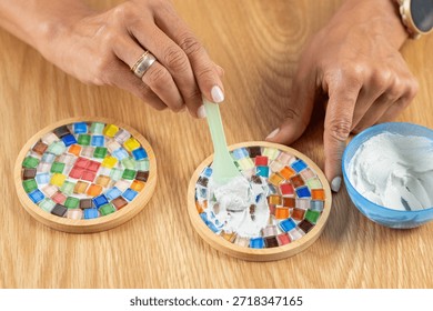 Adding a protective topcoat to handmade coasters as part of her craft routine. Emphasizes controlled application, material care, and decorative clarity.