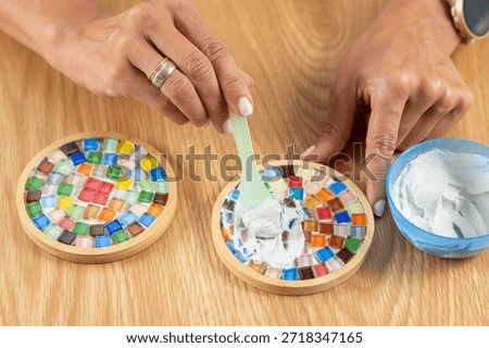 Adding a protective topcoat to handmade coasters as part of her craft routine. Emphasizes controlled application, material care, and decorative clarity.