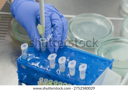 Adding small doses of various components of liquid origin to a small test tube on a stand in the laboratory.