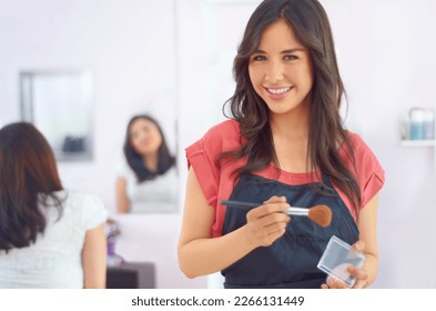 Adding a touch of powder. A young makeup artist standing in her studio.