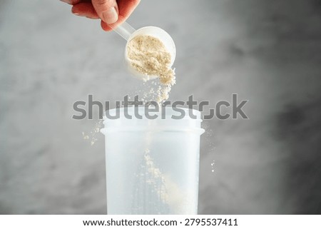 Adding whey protein powder to shaker bottle for fitness shake preparation