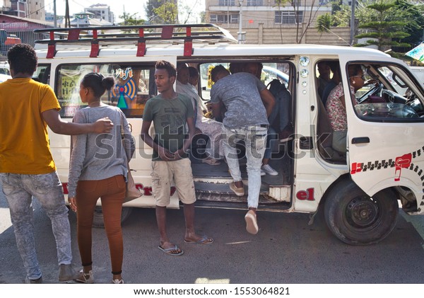 Addis Ababa, Ethiopia - December\
20, 2018: Crowd of local people in the bus station in Addis Ababa,\
Ethiopia, with local people getting into a car used as\
bus.