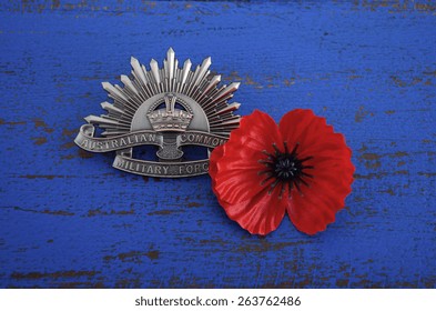 ADELAIDE, AUSTRALIA - MARCH 18, 2015: Australian Anzac WWI Rising Star Hat Badge With Red Remembrance Poppy On Dark Blue Wood Background.