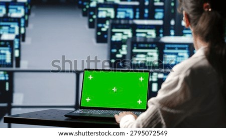 Adept computer scientist in server farm housing high end systems capable of quickly and efficiently performing complex computations and data analysis, using mockup laptop to avoid hazards.
