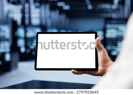 Adept IT developer using mockup tablet to check operational server rows, close-up; racks in computer network security data center providing processing and memory resources for several workloads.