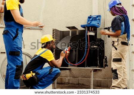 Adept repairman expertly refilling freon in HVAC system while using benchmarking tools to precisely measure the pressure in air conditioner, ensuring optimal cooling performance