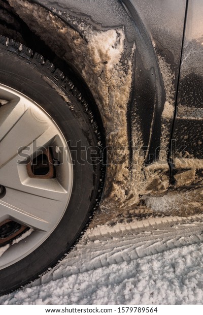 Adhered to the body of the car dirty\
snow from the road. photo close-up of car details. rusty car, metal\
corrosion and traces of reagents, winter Moscow\
city.