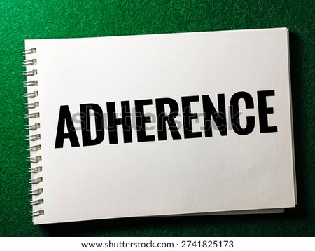 Adherence concept on notepad representing compliance conformity regulation policy obedience standards governance in business context. 