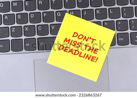 Adhesive note on top of laptop with text don't miss the deadline