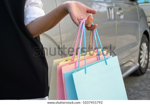 adies handbags with
colorful bag after shopping at department stores, focus her hand
and car background.