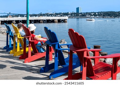 Adirondack chairs with people looking to the harbour - Powered by Shutterstock