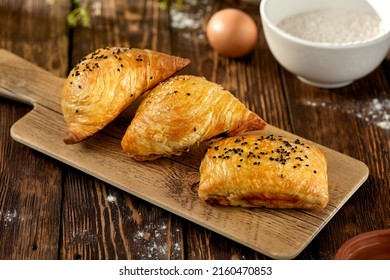 aditional uzbek pastry - samsa with meat. Uzbek pies with meat and puff dough on wooden background in rustic style. Meat samosa with ingredients. East pastry