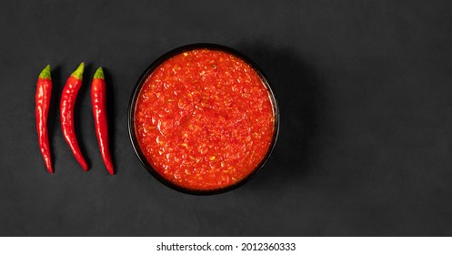 Adjika on a black background. Hot chili peppers harissa sauce. Homemade rose harissa in a bowl. Copy space, top view, flat lay. - Shutterstock ID 2012360333