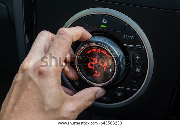 Adjust air conditioner in car\
, Driver hand tuning temperature control in car air conditioning\
system