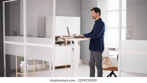 Adjustable Height Desk Stand In Office Using Computer - Powered by Shutterstock