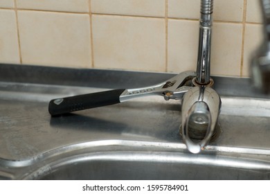 An Adjustable Spanner Lies On A Rusty Kitchen Faucet. Incomplete Repair Process, No People