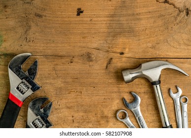 Einstellbarer Schlüssel und Hammer auf braunem Holzschreibtisch