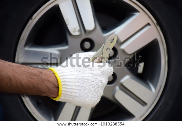 Adjustable\
wrench in the hands of the car mechanic. Auto Mechanic with\
Adjustable wrench in Hands front of the\
wheel