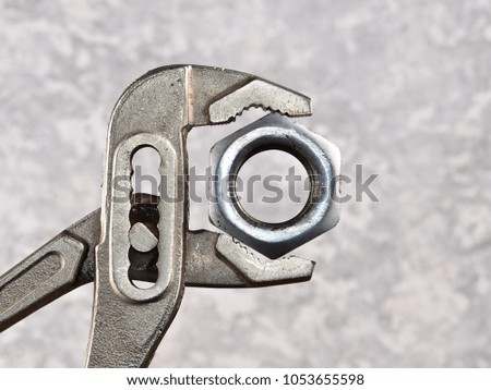adjustable wrench with a nut on the background of a concrete wall
