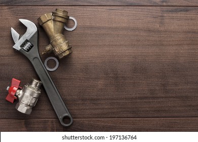 adjustable wrench and pipes on the wooden background