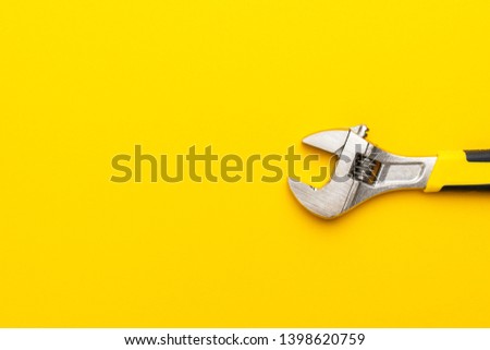 adjustable wrench with yellow handle on the yellow background