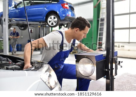 adjusting the headlights on the car by mechanics in a garage 