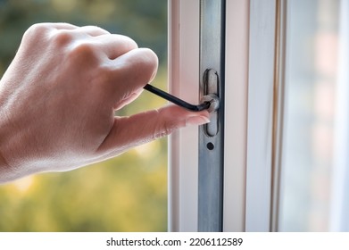 adjusting the white plastic window. a worker uses a hexagon to repair a window. 