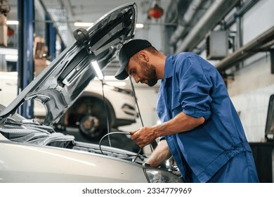 Adjusts the cable. Auto mechanic working in garage. Repair service. - Powered by Shutterstock