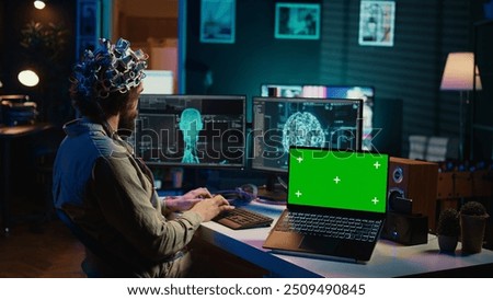 IT admin coding and using EEG headset to upload brain into green screen laptop, gaining immortality. Neuroscientist engineering transhumanism experiment on chroma key device, camera B