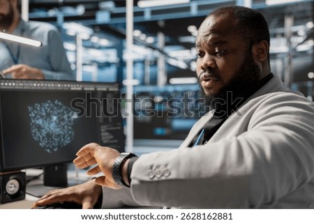 Admin in data center checking time during late shift while working on PC. Server room worker under deadline pressure inspecting settings and verifying final system configurations