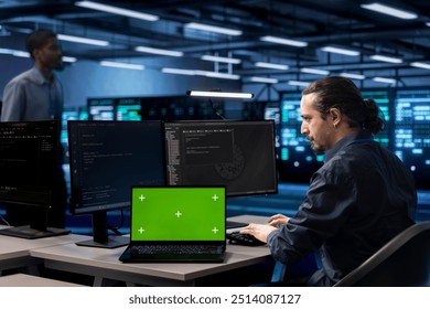 Admin in data center using system monitoring software on isolated screen laptop to identify root cause of malfunctions. IT expert in server farm repairing infrastructure with chroma key notebook