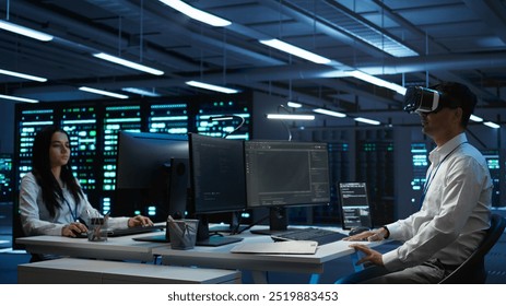 Admin in data center using virtual reality tech to ensure system can handle networking tasks. Server room worker wearing VR headset to track network traffic with PC, making improvements, camera B