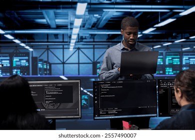 Admin doing routine maintenance in data center to extend equipment life span and avoid downtime. Worker monitoring servers for issues such as overheating or power fluctuations
