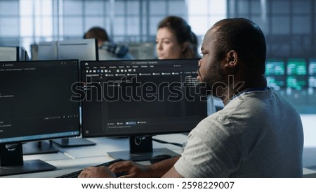 Admin in server hub tasked with protecting valuable data against hacking attack on computers. African american worker safeguarding data center against unauthorized access and vulnerabilities, camera A