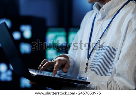Admin in server room future proofing network from downtimes and unexpected system failures using laptop, close up. Employee ensuring reliable operations and increased data security