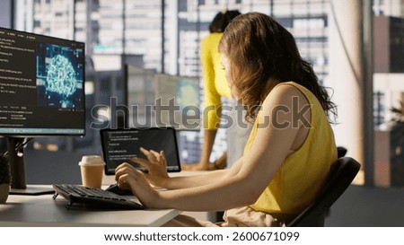 Admin tests on computer and tablet to optimize artificial intelligence machine learning models for performance and accuracy. IT worker in office analyzing and interpreting complex AI data, camera A
