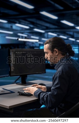 Admin typing on desktop PC in server farm establishment, ensuring data remains shielded from potential threats. IT specialist coding at computer desk, safeguarding data center against malicious access