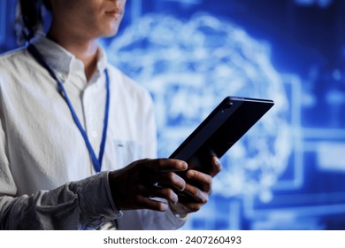Admin using tablet in server room to maintenance artificial intelligence neural networks simulating human thought processes. High tech establishment worker does checkup on AI systems