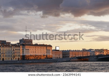 Administrative buildings and residential buildings on the embankment of the river in the light of the setting sun. Evening urban landscape of the old city. City at sunset.