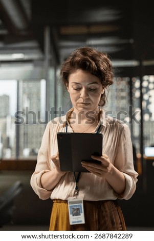 Administrator uses digital tools and analytics to improve corporate strategy, reviewing finance data insights on tablet to foster innovation and development in a modern office setting.